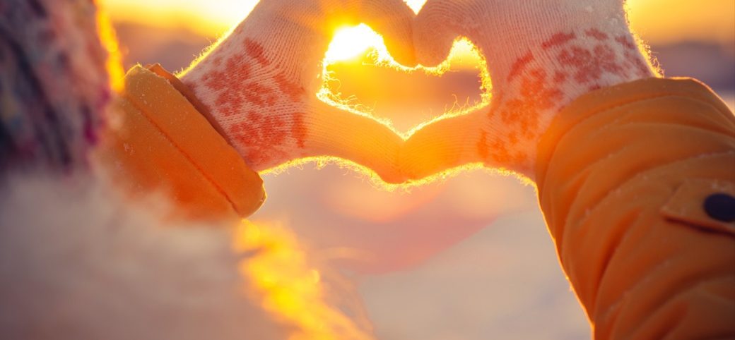 Hands in the shape of a heart wearing winter gloves