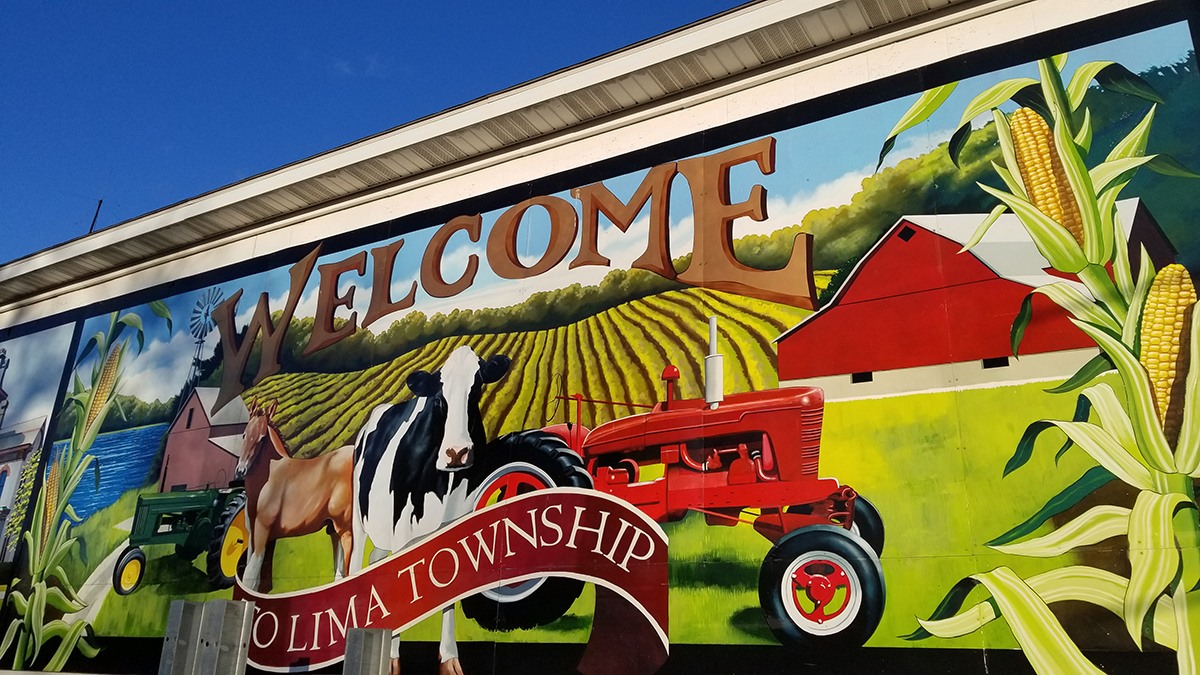 Mural of a farm saying Welcome to Lima Township featuring a cow, horse, and tractor