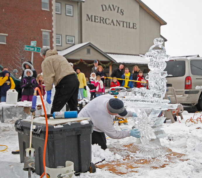 group of onlookers watching man carve ice scultpure