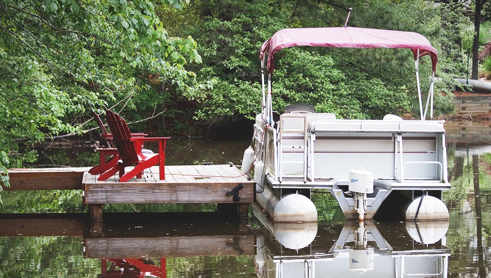 Boat in a lake near a dock with two chairs