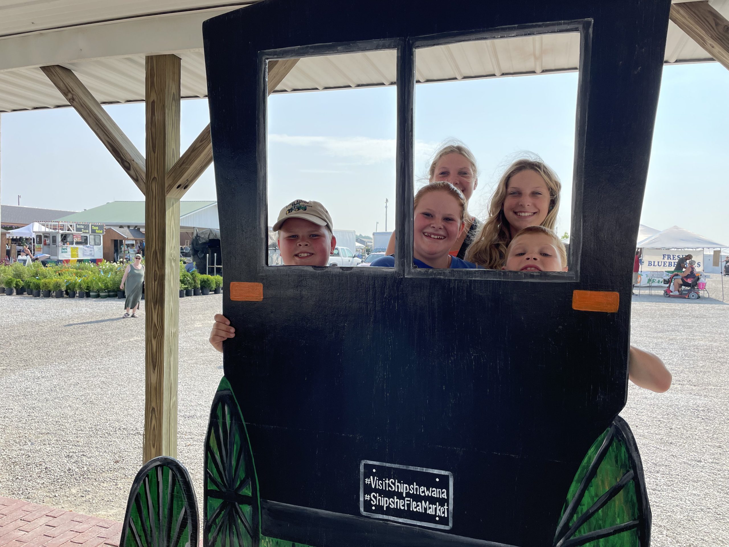 Kids posing behind an Amish buggy.